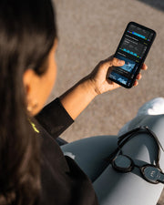 Woman sitting and looking at a swim tracker app with goggles on her knee