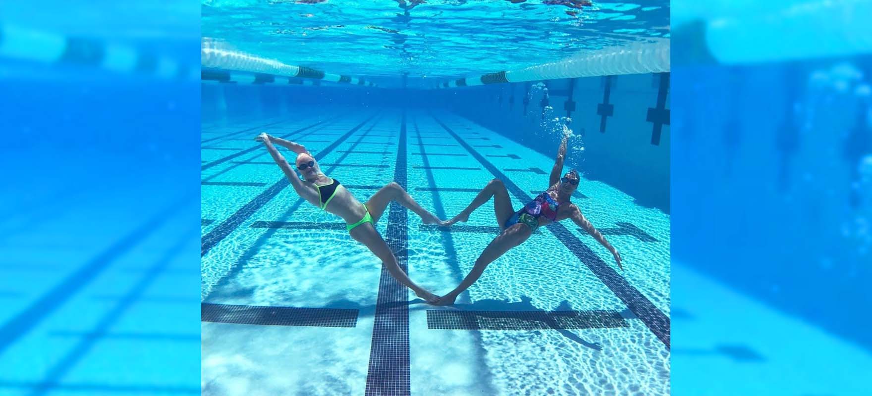 two swimmers posing as a heart shape under water