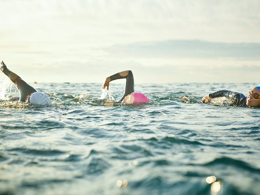 Three swimmers in an open body of water wearing Form swim goggles
