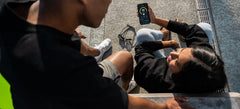 Swimmers reviewing swim progress data on a smartphone after a pool session