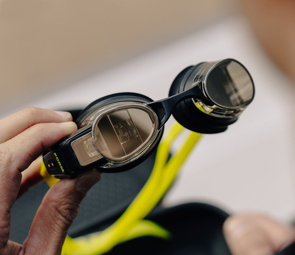 Swimmer adjusting FORM smart swim goggles with display visible