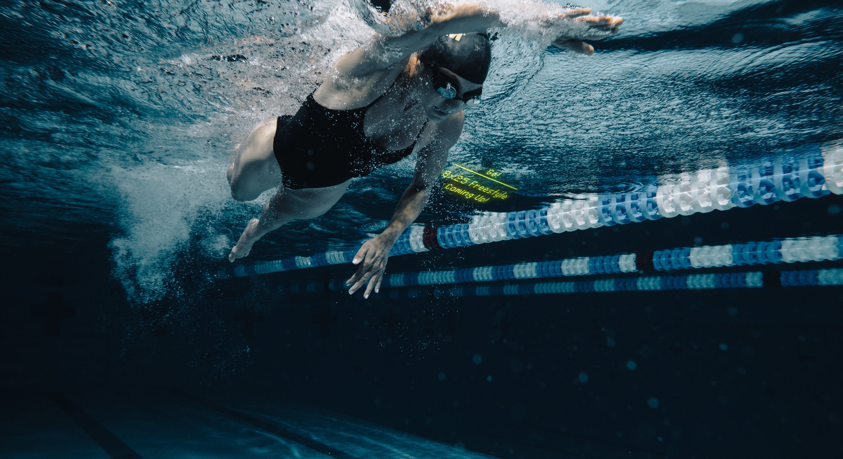 Dynamic underwater action shot of a swimmer using smart goggles, illustrating powerful swimming technique.