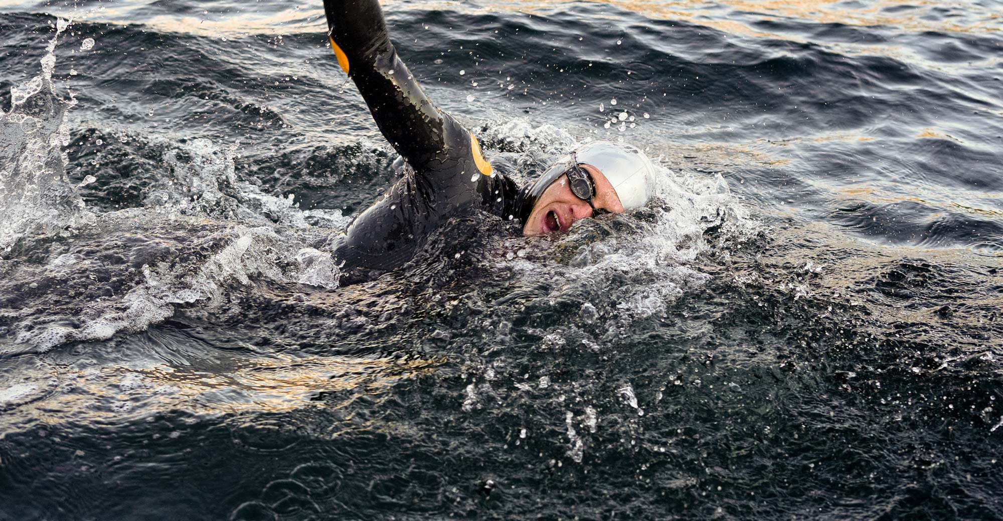 Man swimming front crawl in open water with swim tracker in his goggles